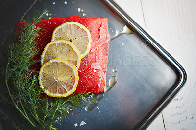 Buy stock photo Fish, tuna and cooking with lemon, above and metal plate with oil, herbs or meal prep for seafood. Food, leaves and citrus for nutrition, diet or start process for dinner, wellness or benefit in home