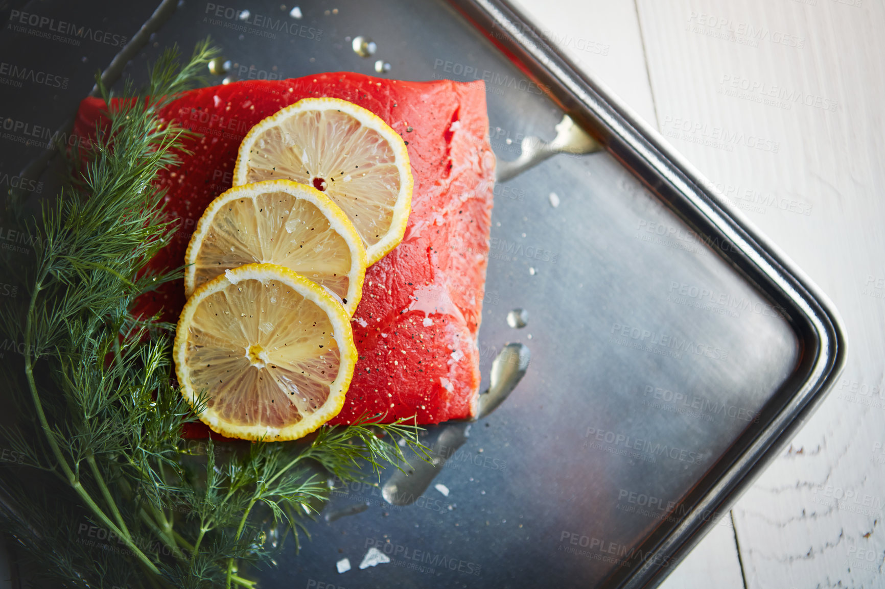 Buy stock photo Fish, tuna and cooking with lemon, above and metal plate with oil, herbs or meal prep for seafood. Food, leaves and citrus for nutrition, diet or start process for dinner, wellness or benefit in home