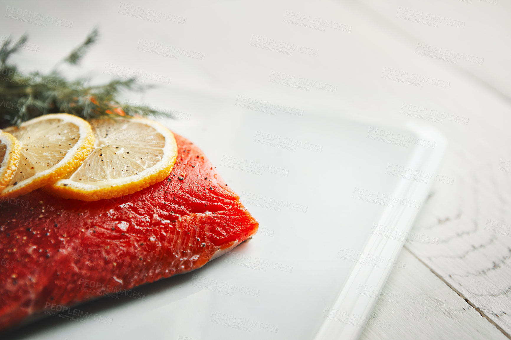 Buy stock photo Shot of a raw piece of meat garnished with slices of lemon