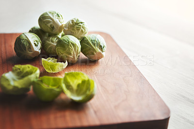 Buy stock photo Brussels sprouts, wooden board and cooking in kitchen for health, lunch and nutrition for wellness. Vegetables, food and chopping block on table, leaves and meal prep for dinner on vegan diet in home