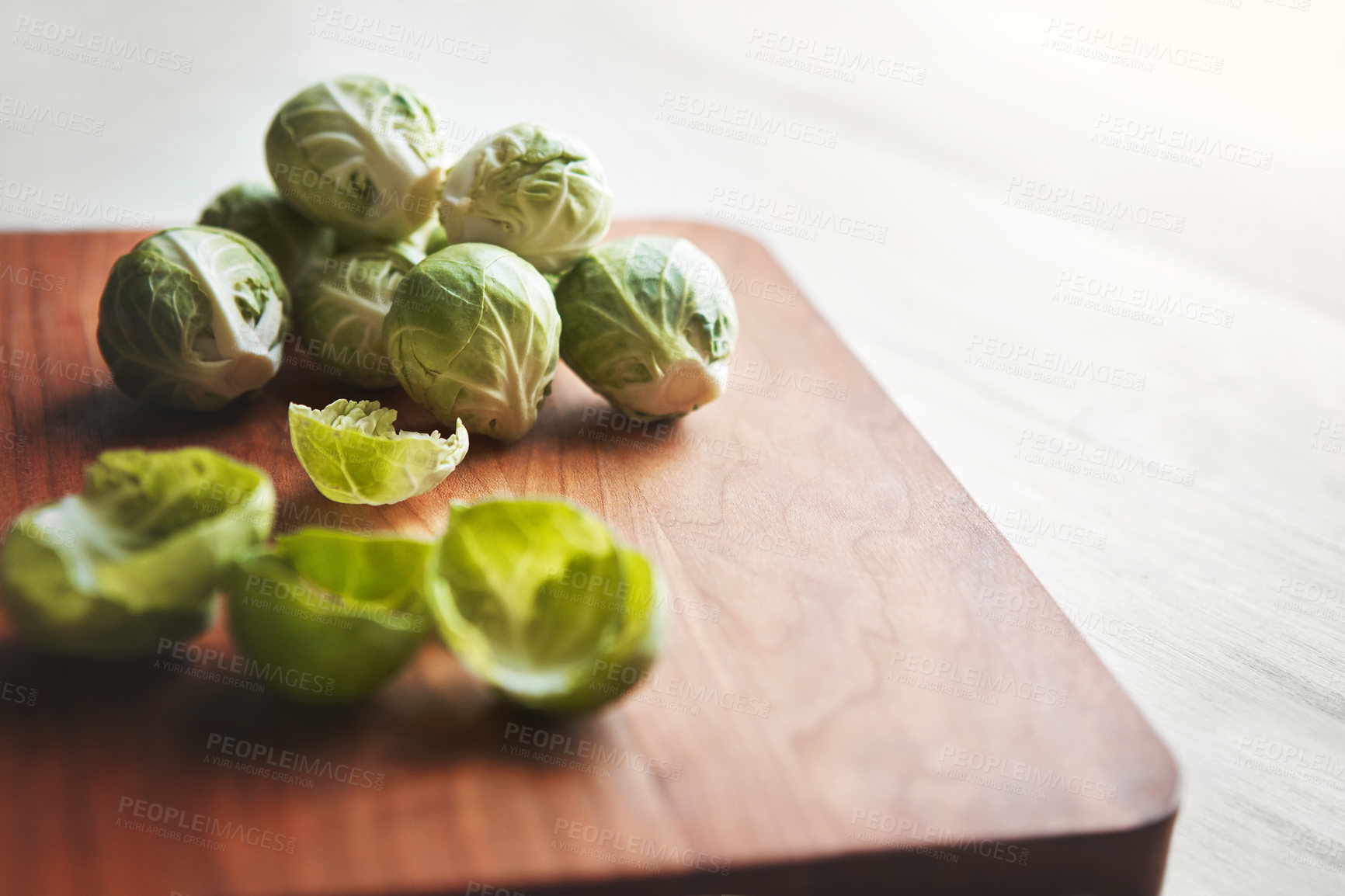 Buy stock photo Brussels sprouts, wooden board and cooking in kitchen for health, lunch and nutrition for wellness. Vegetables, food and chopping block on table, leaves and meal prep for dinner on vegan diet in home