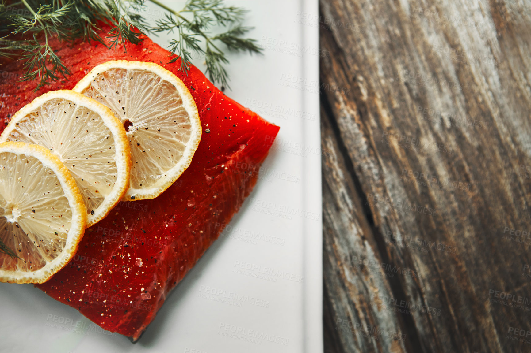 Buy stock photo Shot of a raw piece of meat garnished with slices of lemon