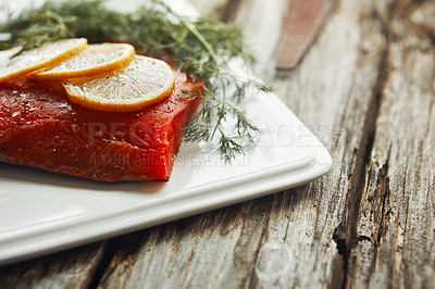 Buy stock photo Shot of a raw piece of meat garnished with slices of lemon