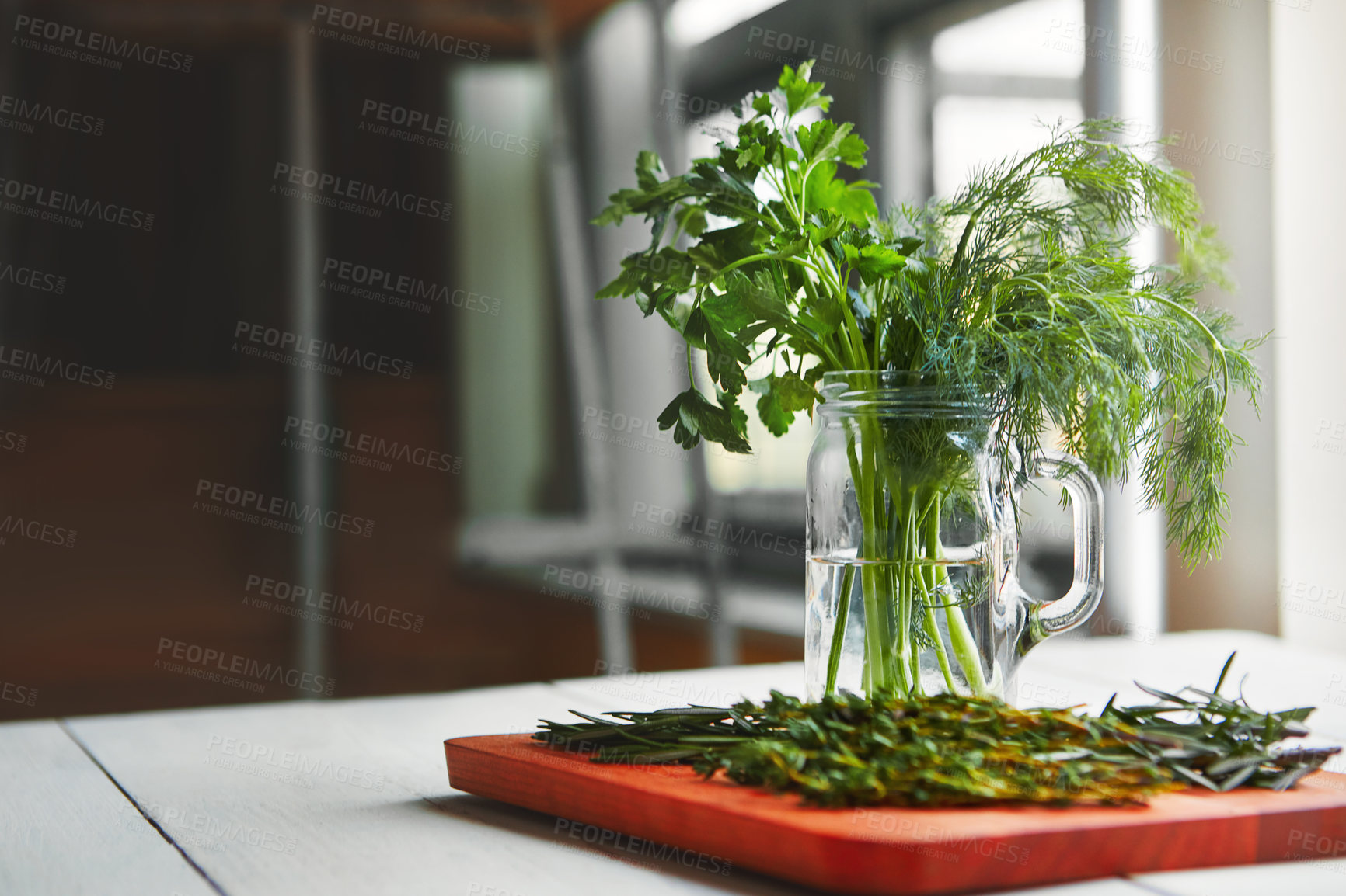 Buy stock photo Shot of fresh herbs in a glass of water on a kitchen table