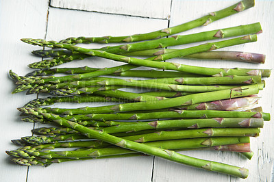 Buy stock photo Asparagus, kitchen and food on table for health, lunch or decision with nutrition for wellness. Organic vegetable, cooking and choice for benefit on counter, detox or meal prep for vegan diet in home