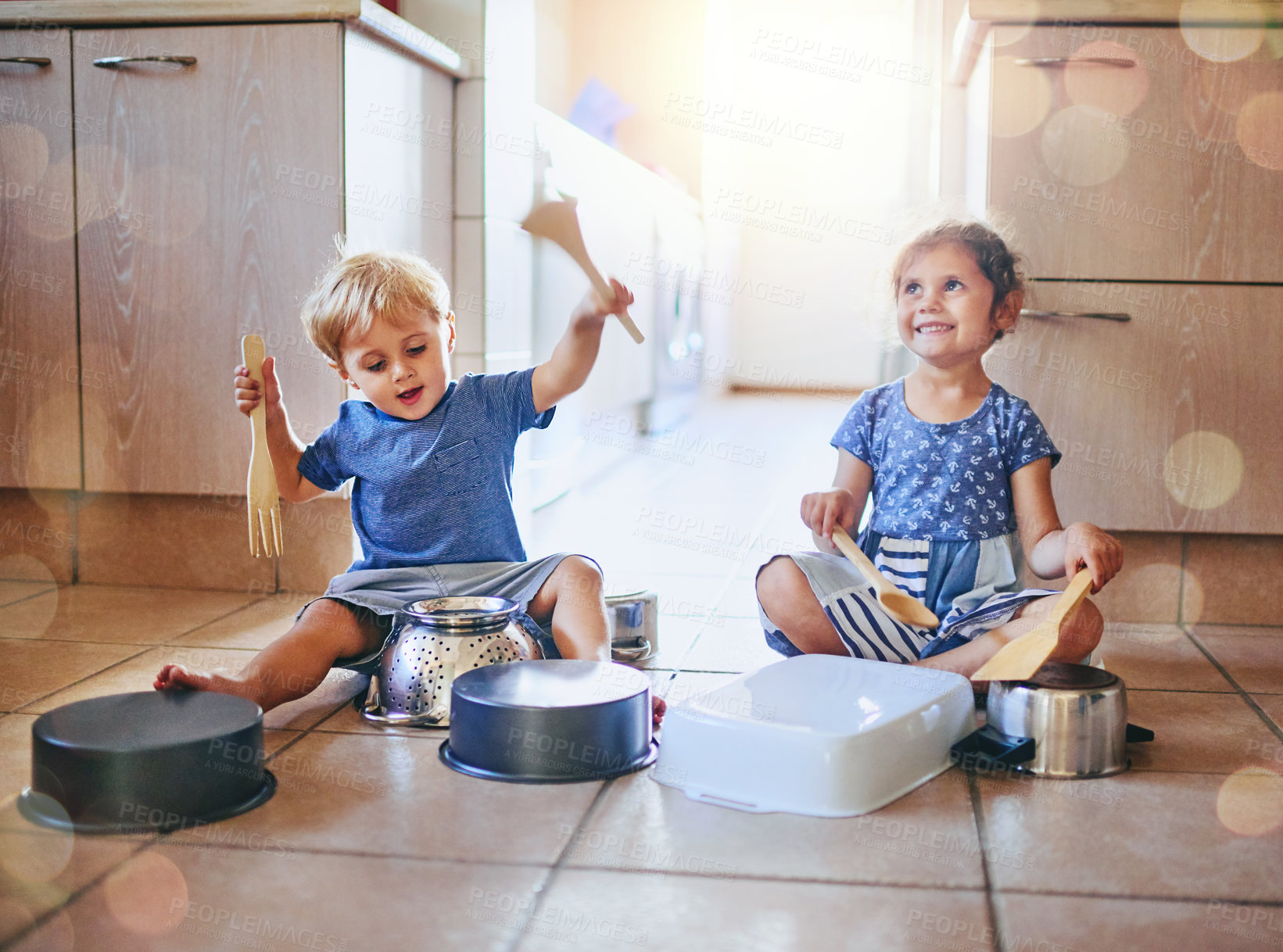 Buy stock photo Shot of two adorable children playing on a drum set made of pots on the kitchen floor