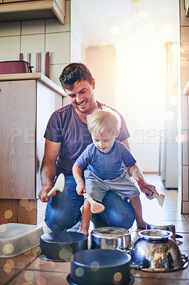 Buy stock photo Shot of a father watching his young son as he plays drums on pots on the kitchen floor