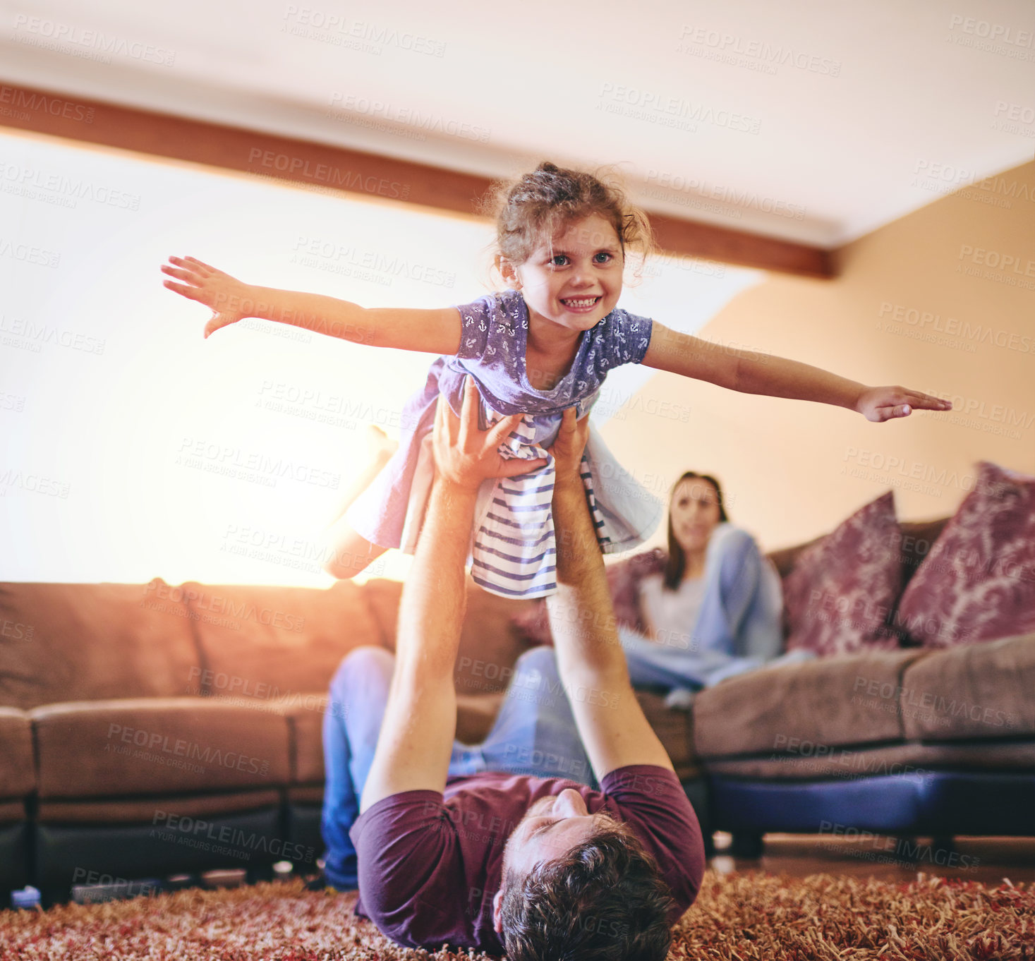 Buy stock photo Shot of a happy little girl playing in the lounge with her father while her mother watches