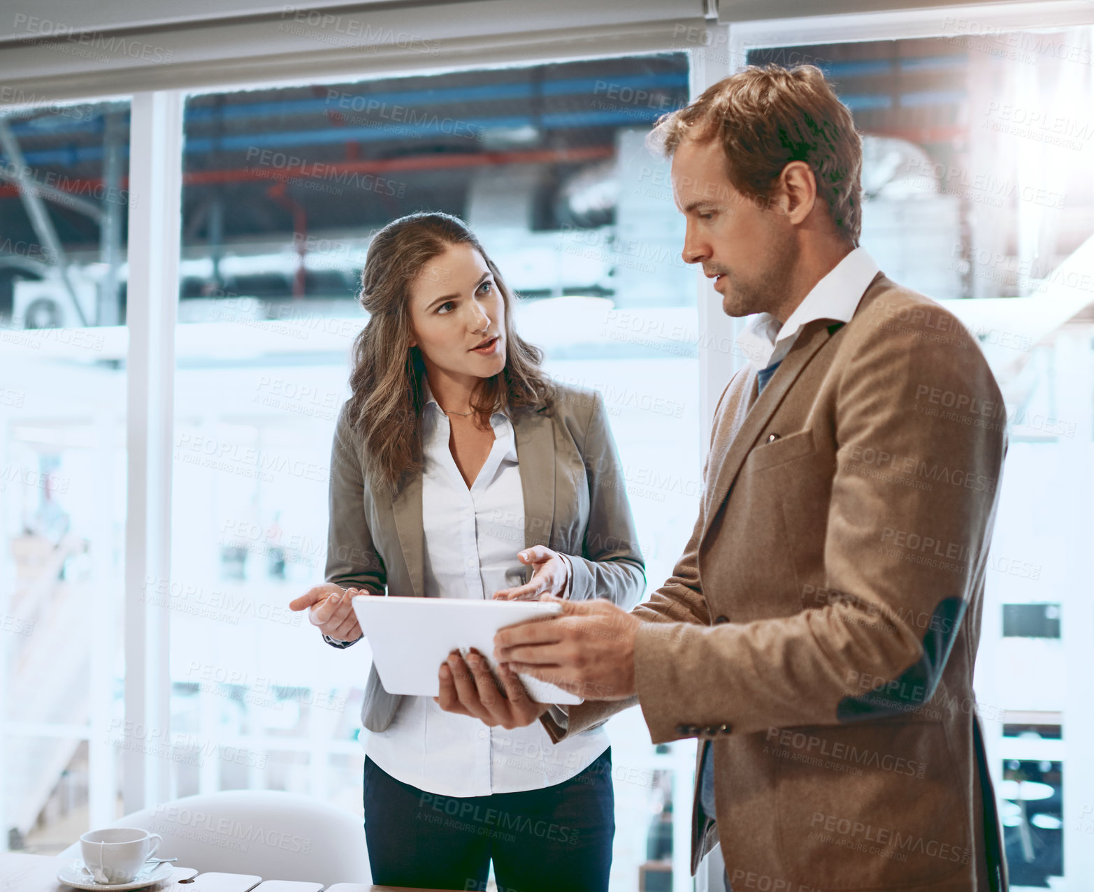 Buy stock photo Cropped shot of two businesspeople working together on a tablet in their office