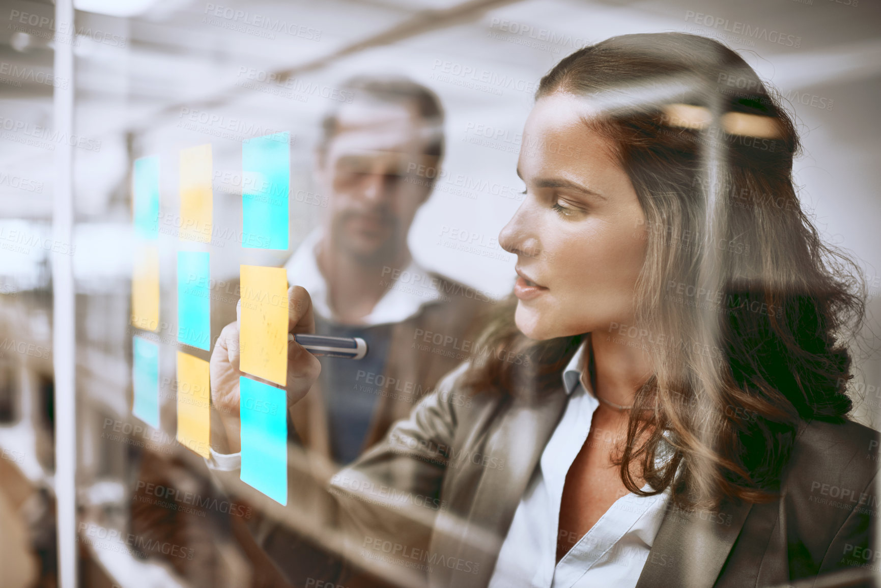 Buy stock photo Cropped shot of two businesspeople working on a glass wipe board in their office