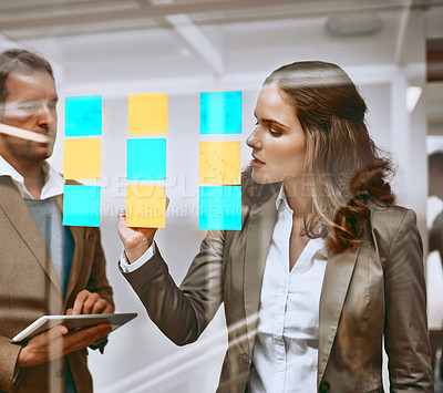 Buy stock photo Cropped shot of two businesspeople working on a glass wipe board in their office