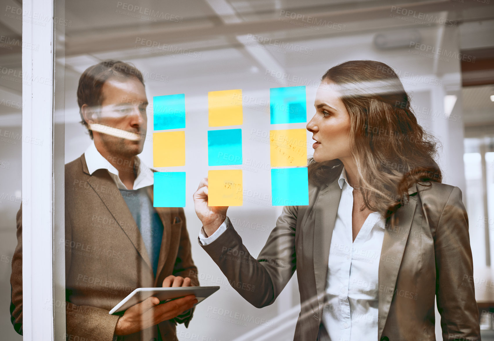 Buy stock photo Cropped shot of two businesspeople working on a glass wipe board in their office