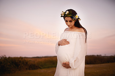Buy stock photo Shot of a young pregnant woman holding her belly outdoors