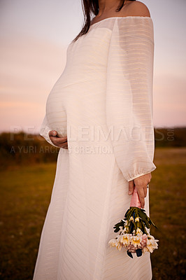 Buy stock photo Shot of a young pregnant woman holding her belly outside