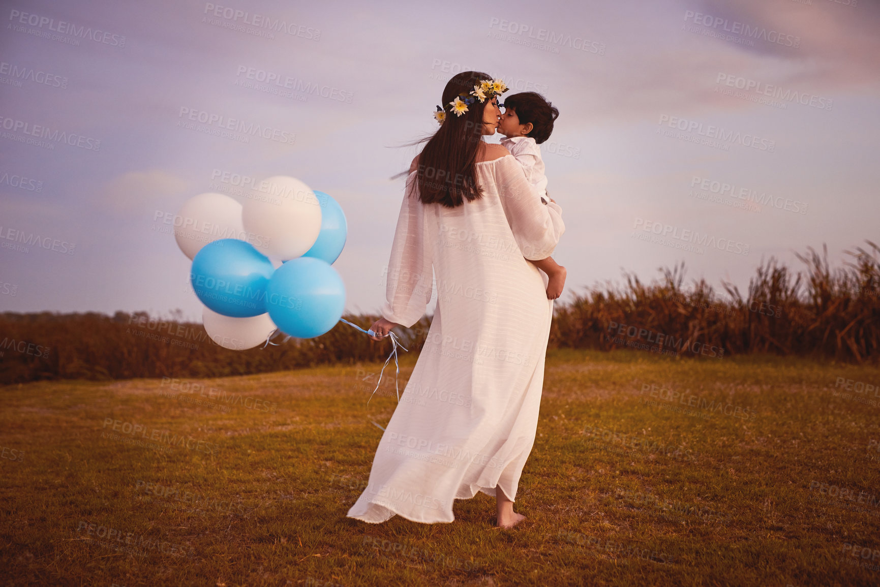 Buy stock photo Shot of a young mother kissing her son whilst holding him outdoors