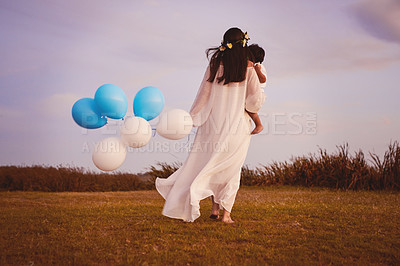 Buy stock photo Rearview shot of a young mother and her son walking while holding blue and white balloons outdoors