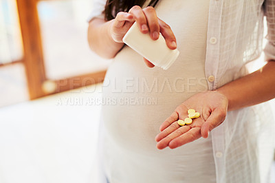 Buy stock photo Cropped shot of an unrecognizable pregnant woman taking medication at home