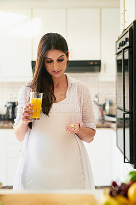 Buy stock photo Shot of a young pregnant woman taking medication with orange juice at home