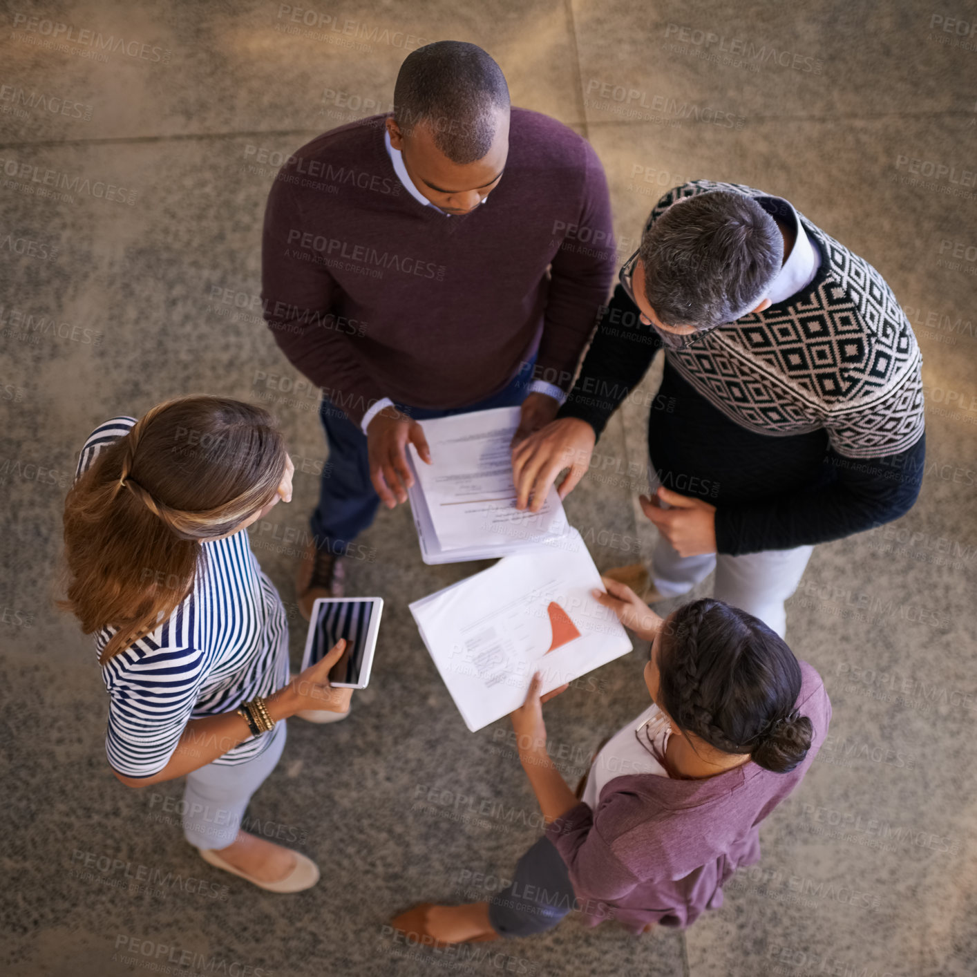 Buy stock photo High angle shot of a group of work colleagues brainstorming and coming up with ideas in a circle in the office