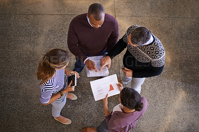 Buy stock photo High angle shot of a group of work colleagues brainstorming and coming up with ideas in a circle in the office