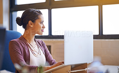 Buy stock photo Shot of a young woman working on her laptop in the office and looking focused