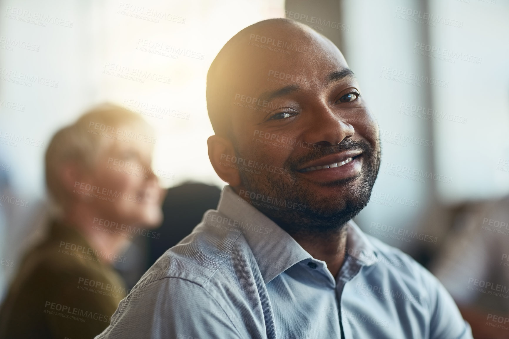 Buy stock photo Confident, happy and motivated businessman sitting in an office meeting. Face of a smiling African entrepreneur feeling satisfied with his job choice while attending a presentation or workshop