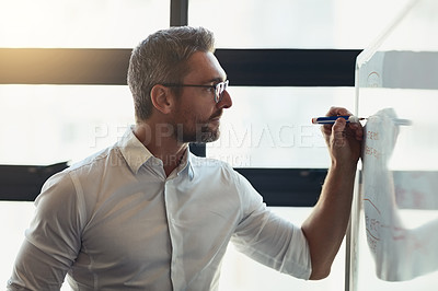 Buy stock photo Cropped shot of a mature businessman working on a whiteboard in his office