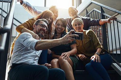 Buy stock photo Cropped shot of a group of business colleagues sitting outside on steps and taking a group photo together