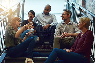 Buy stock photo Cropped shot of a group of business colleagues sitting outside on steps and talking to each other