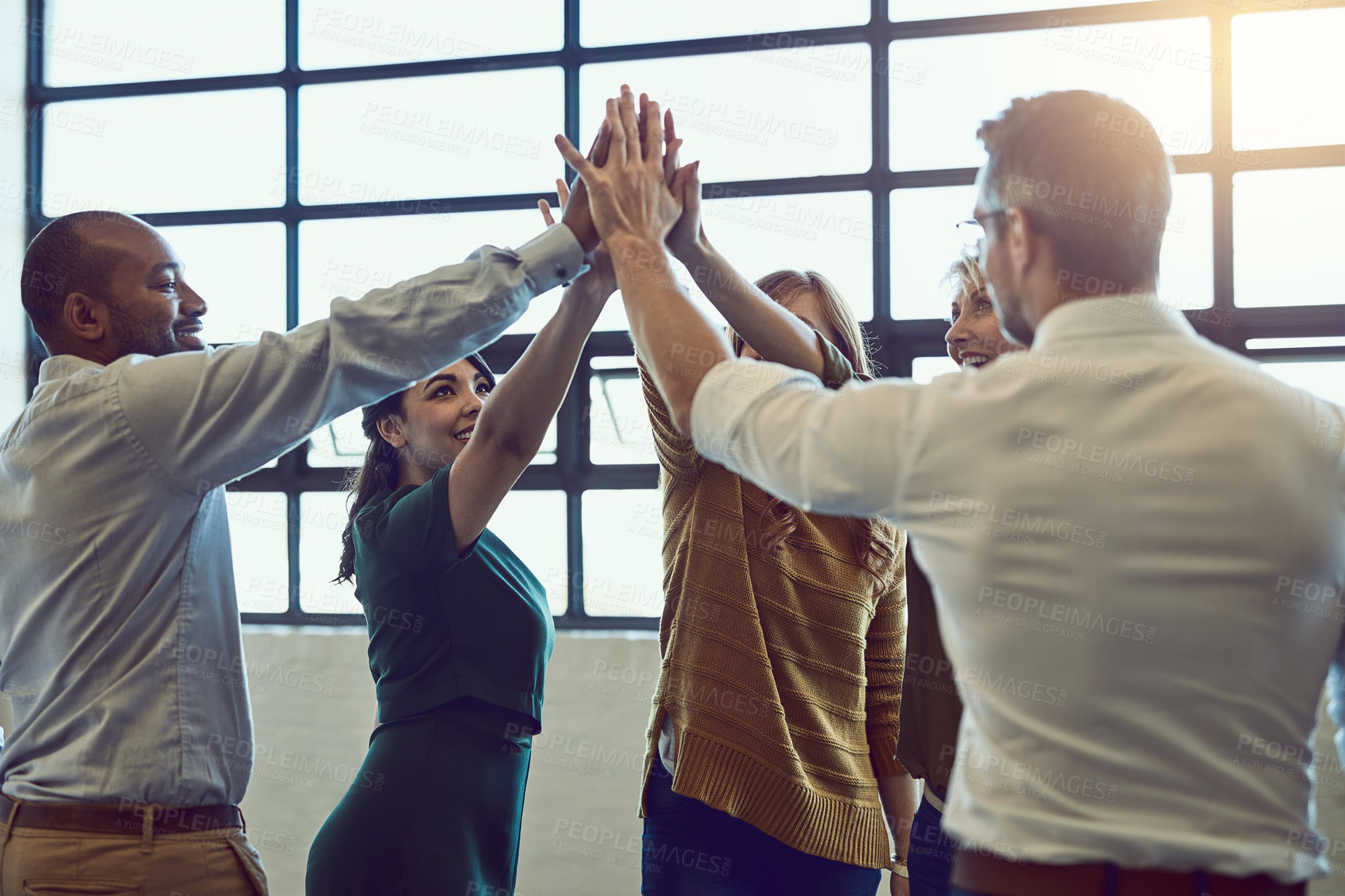 Buy stock photo Team of cheerful colleagues celebrate with high five after hearing good news at the office. Diverse team winning and supporting each other. Professional and successful people standing together.