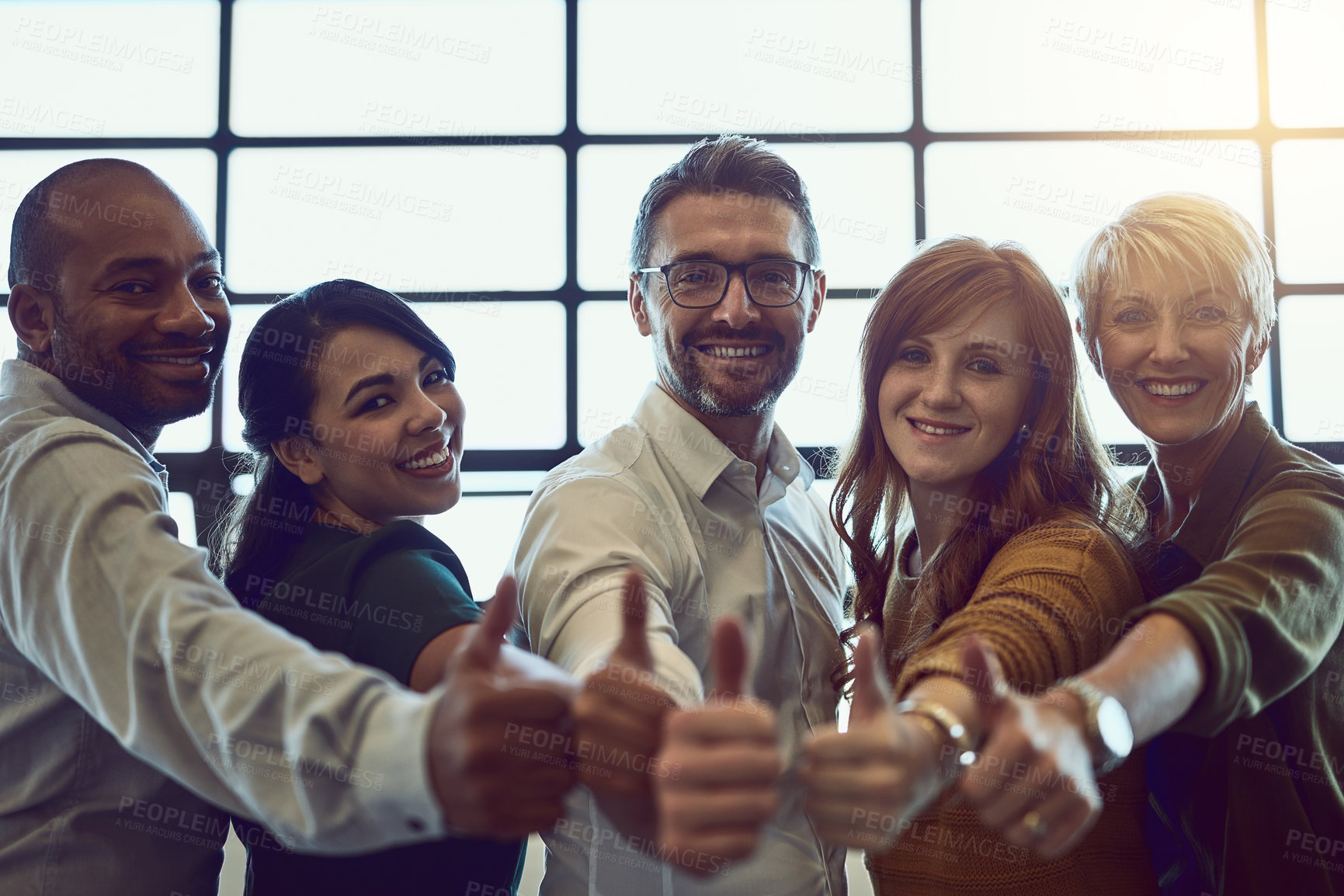 Buy stock photo Portrait of a team of colleagues giving a thumbs up in a modern office