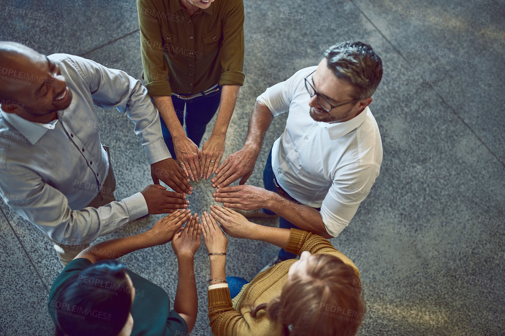 Buy stock photo High angle shot of a group of colleagues joining their hands in solidarity at work