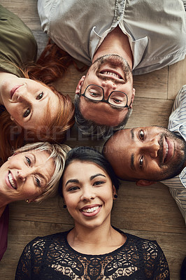 Buy stock photo High angle portrait of a group of colleagues lying together in a circle on the floor at work