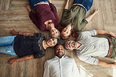 Buy stock photo High angle portrait of a group of colleagues lying together in a circle on the floor at work