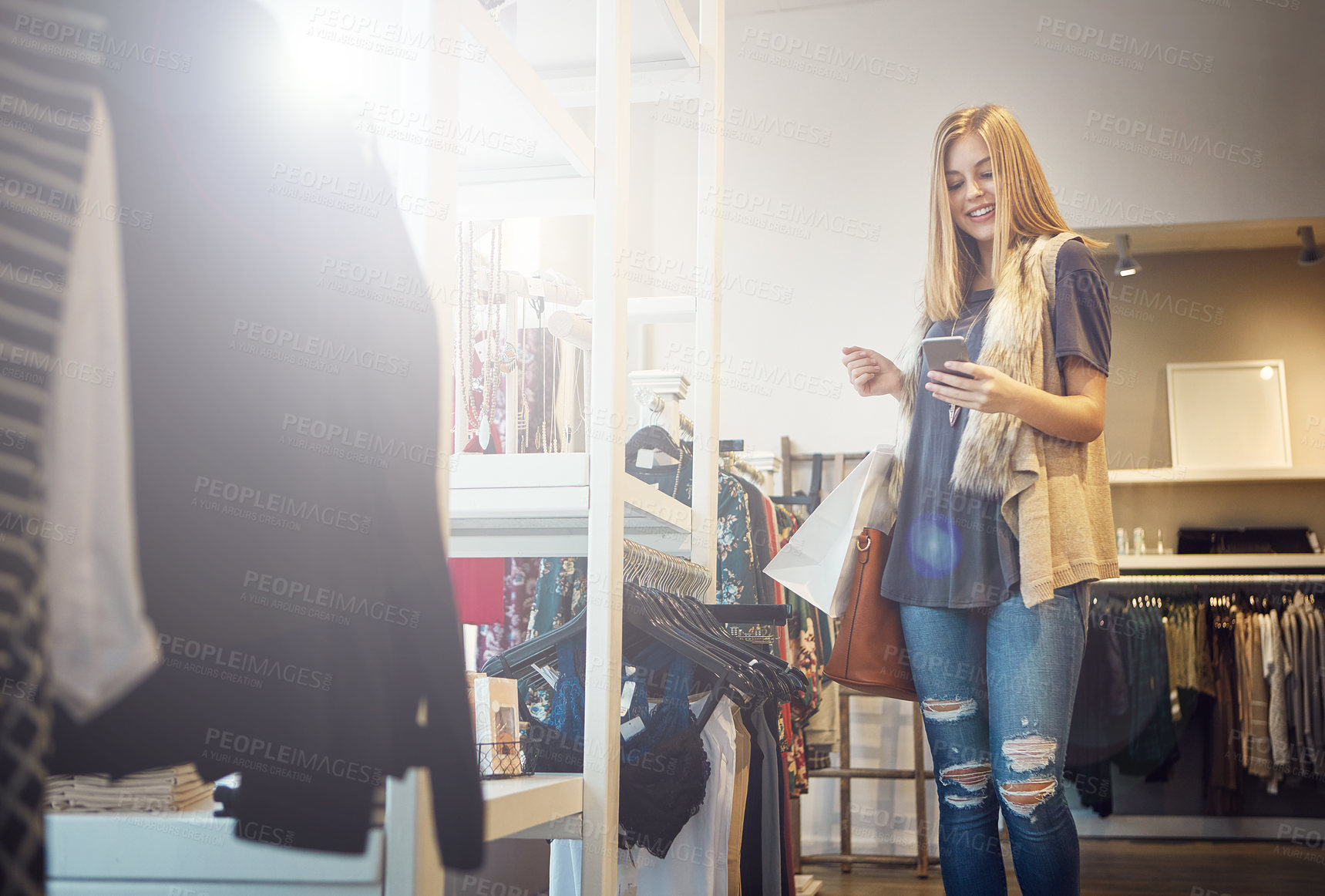 Buy stock photo Shot of a young woman using her cellphone while out shopping
