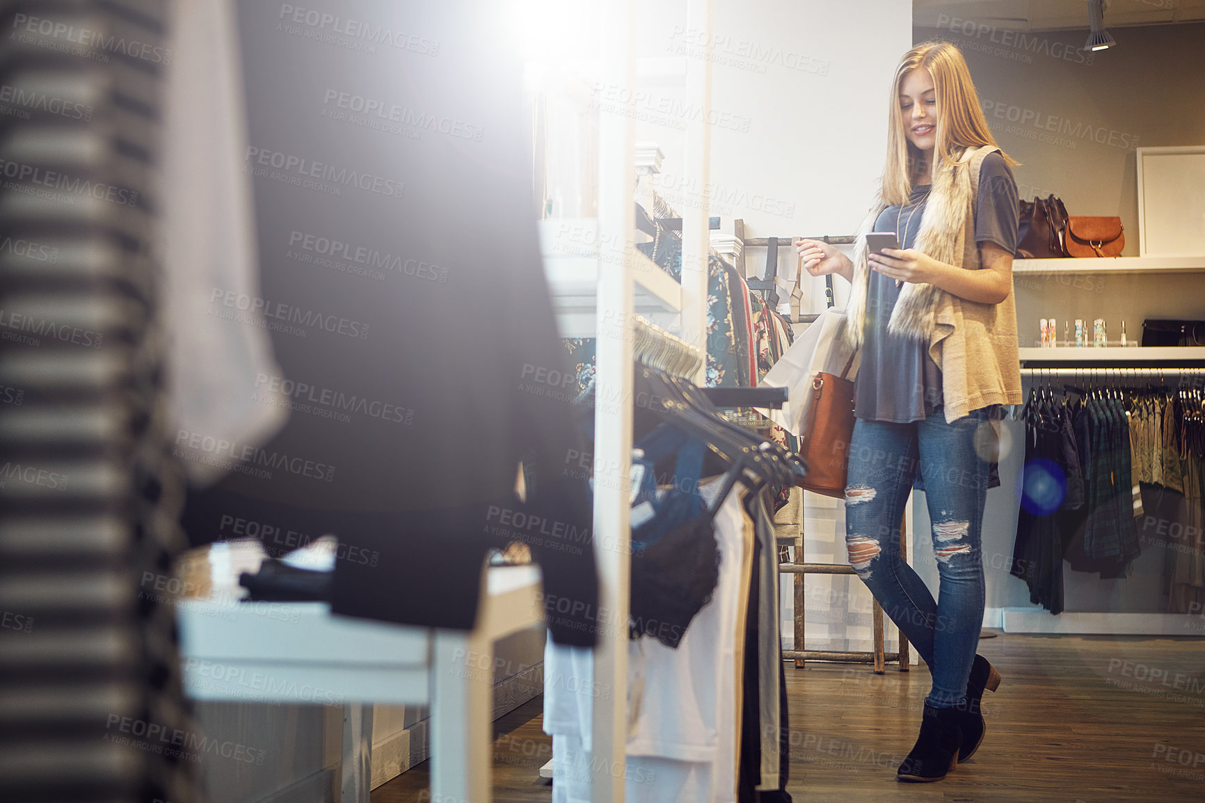 Buy stock photo Shot of a young woman using her cellphone while out shopping