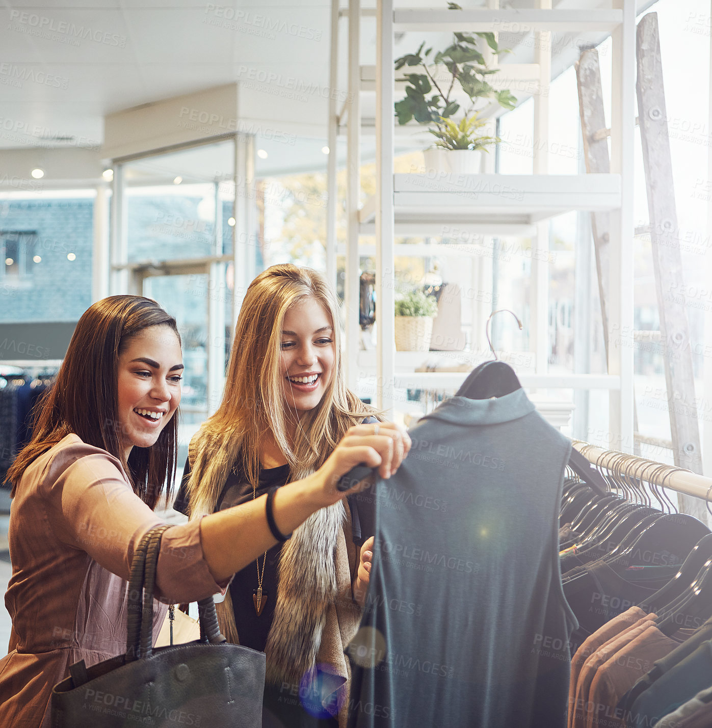 Buy stock photo Shot of a young woman holding up an item that she picked out in a clothing store