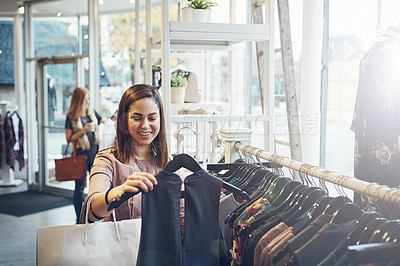 Buy stock photo Shot of a young woman holding up an item that she picked out in a clothing store