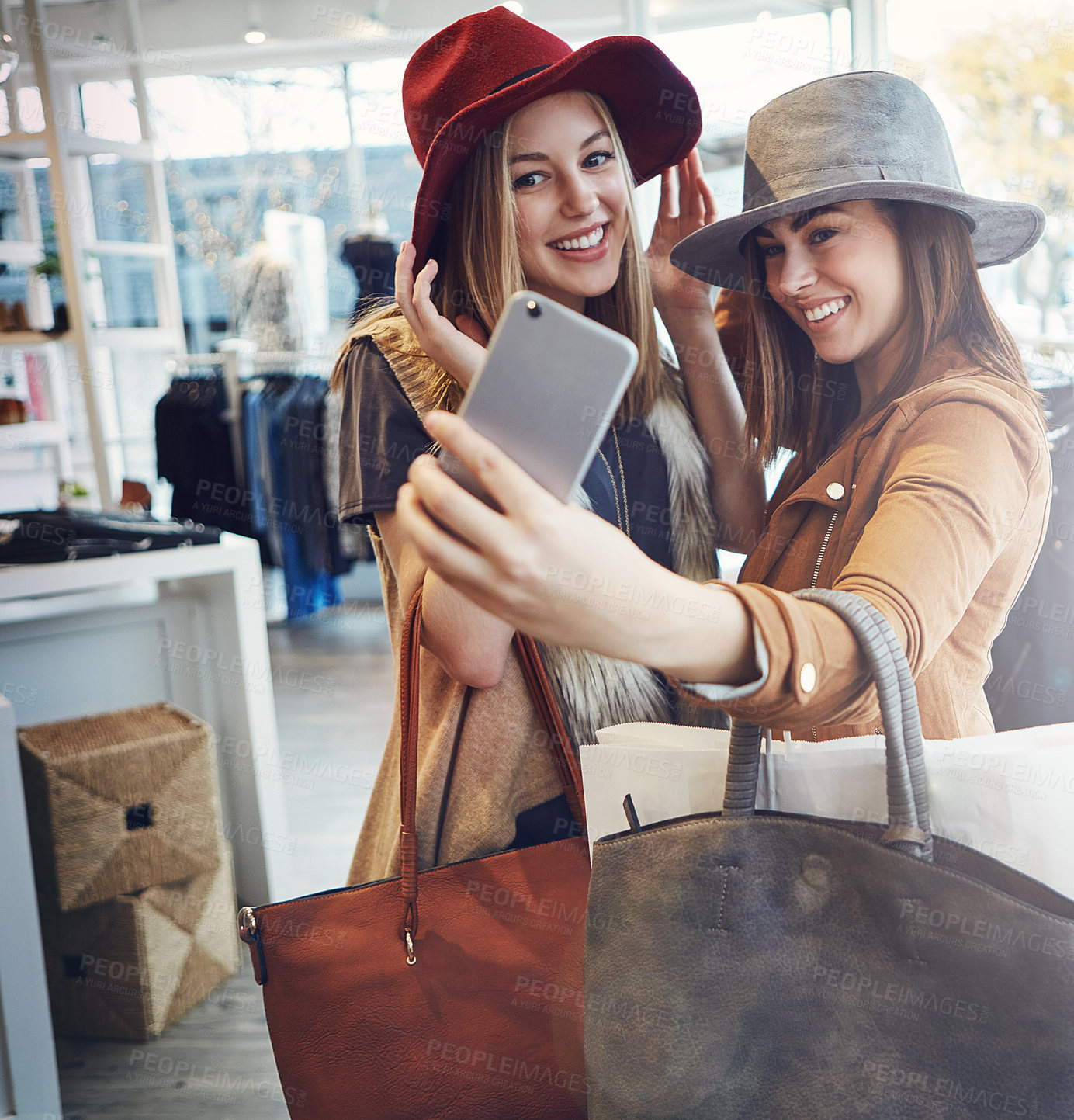 Buy stock photo Cropped shot of two young girlfriends snapping selfies while out on a shopping spree