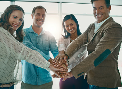 Buy stock photo Cropped shot of a motivated group of businesspeople standing in the office with their hands in a huddle