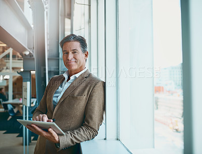 Buy stock photo Shot of a mature businessman standing in the office and making notes on his tablet for the business