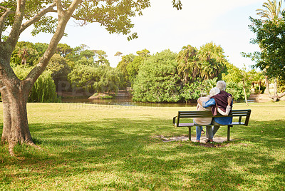 Buy stock photo Rearview shot of an affectionate senior couple relaxing on a park bench