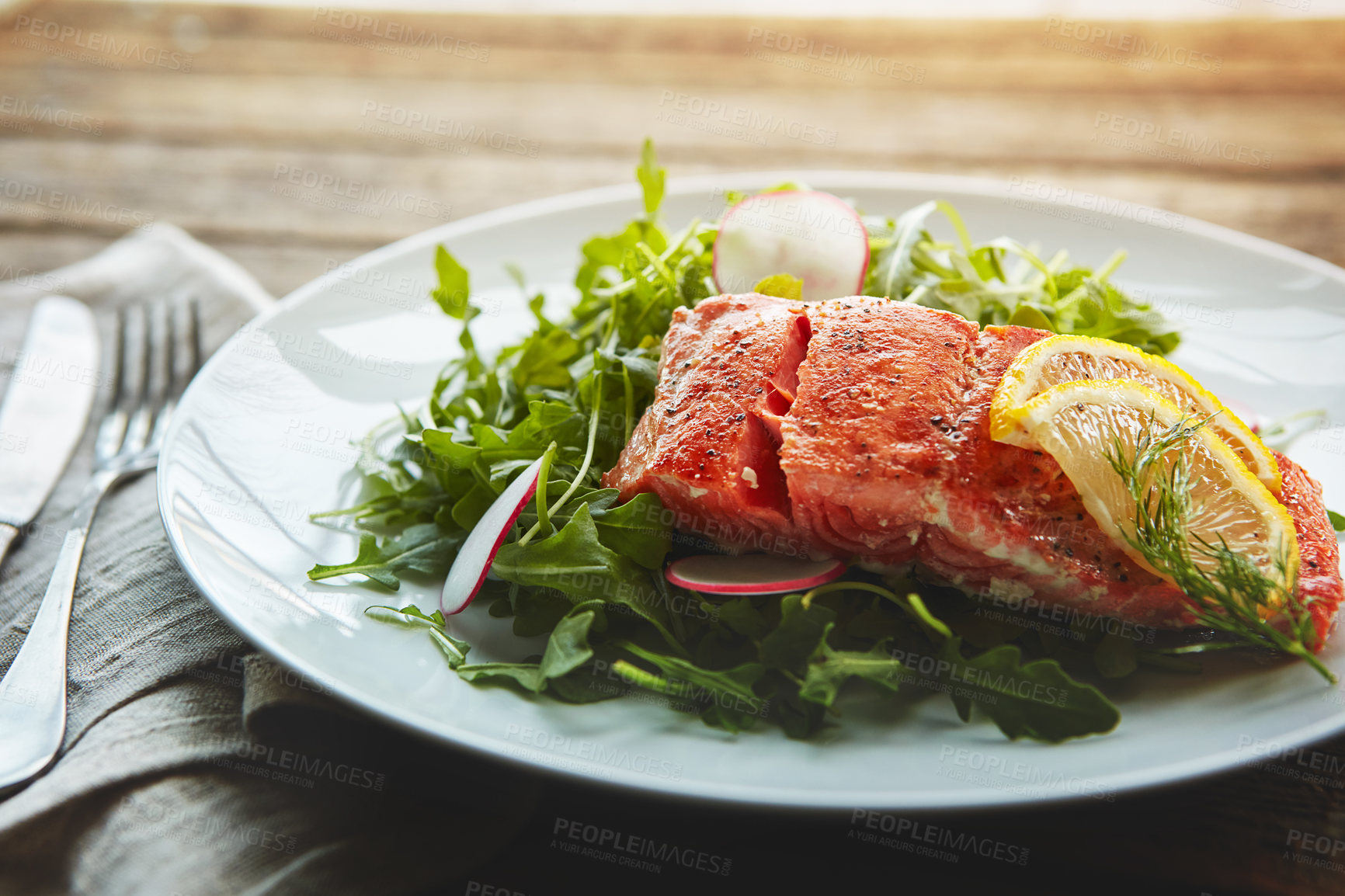 Buy stock photo Food, fish protein and salad with nutrition for wellness, lunch plate and lose weight with pescatarian diet. Salmon, rocket and plant leaves or herbs for gut health with fine dining on wood table