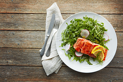 Buy stock photo Cutlery, plate and grilled salmon with salad for healthy, wellness and nutrition fine dining cuisine. Diet, napkin and gourmet meal of fish, arugula and radish with lemon on wooden table from above.