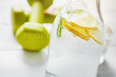 Buy stock photo Shot of a jug of water and dumbbells on a table