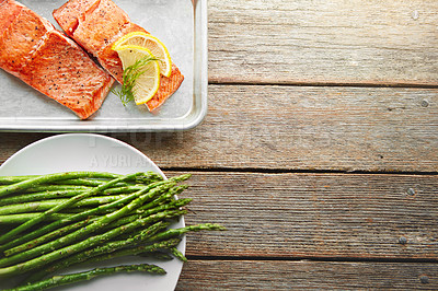 Buy stock photo Shot of a dish with fish and a plate of asparagus on a table