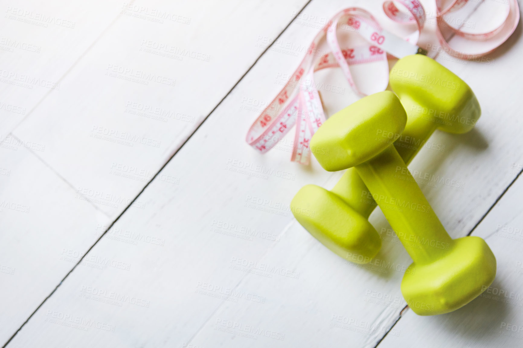 Buy stock photo Shot of dumbbells and a measuring tape on a table