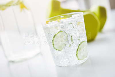 Buy stock photo Glass, dumbbell and fitness with cucumber water on table for vitamin C, detox and weight loss. Green, fruit and cup with ice in healthy drink for nutrition, antioxidants and organic hydration