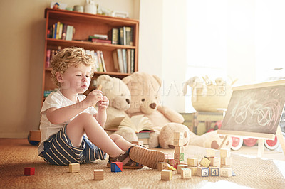 Buy stock photo Shot of an adorable little boy playing with wooden blocks at home