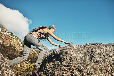 Buy stock photo Shot of a young woman climbing over rocks while out on a hike through the mountains